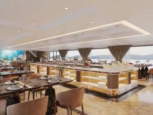 Un comedor con mesas y sillas y ventanas. en Tulip Cruise by HAG, en Ha Long