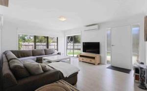 a living room with a couch and a flat screen tv at Beach House Getaway 2 in Smiths Beach