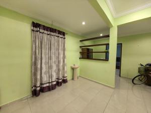 a room with green walls and a curtain in a room at Lagenda Serai Wangi Homestay in Padang Serai