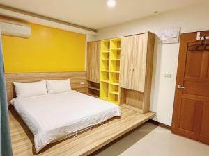 a bedroom with a white bed and a yellow wall at 時光旅舍 in Jincheng
