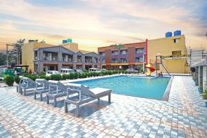 a swimming pool with two benches and a playground at Goa Beach Resort ON Beach in Mandarmoni