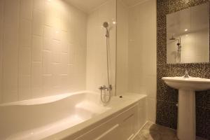 a white bathroom with a tub and a sink at Incheon Soma Hotel in Incheon