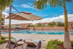 una piscina del complejo con sillas y sombrilla en Emerald Greens Condo Resort en Tampa