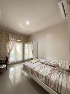 una camera da letto con un letto, una sedia e finestre di SYARIAH - Beautiful 3BR Home - 8 min from Centre by Sakura a Krawang