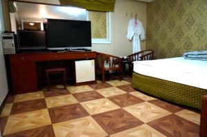 - une chambre avec un lit, une télévision et un bureau dans l'établissement J Motel Gwangalli Busan, à Busan