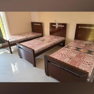 a room with three beds in a room at Al-Jannat Girls Hostel in Lahore