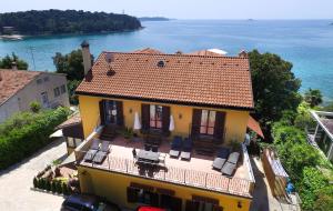 a yellow house with a red roof and the water at Rooms Figarola in Rovinj