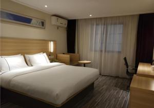 a hotel room with a large bed and a desk at City Comfort Inn Wuhan Wangjiawan Yulong Road Metro Station in Wuhan