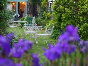 three chairs and a table in a garden with purple flowers at Petit Hotel & Restaurant Old Age in Hokuto