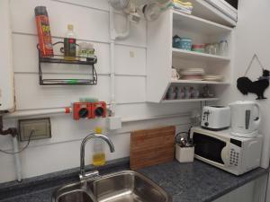 a kitchen with a sink and a microwave at Long Bay Motor Camp in Coromandel Town