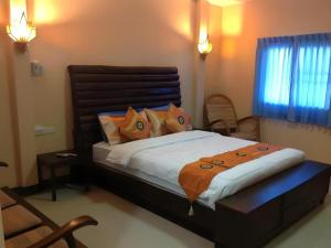 une chambre avec un grand lit avec des oreillers orange dans l'établissement Ruen Kaew Resort, à Phrae
