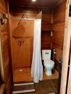 a small bathroom with a toilet and a shower at Whispering Hills in Perean