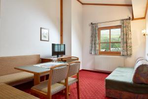 a room with a table and chairs and a television at Sporthotel Kogler in Mittersill