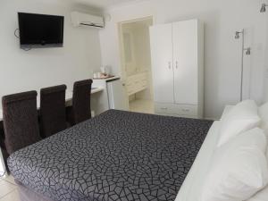 a bedroom with a bed and a desk with a tv at Park View Motel in Gladstone +10 photos