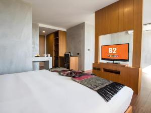 a bedroom with a white bed and a flat screen tv at B2 Udon Thani Boutique and Budget Hotel in Udon Thani