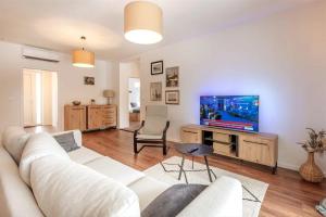 a living room with a white couch and a tv at Villa Grace, a romantic single story villa with a pool in VeliGolji