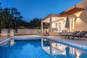 a swimming pool in front of a house at Villa Grace, a romantic single story villa with a pool in VeliGolji