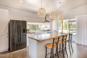 a kitchen with a refrigerator and a bar with stools at LJ's Hideout in Dunsborough