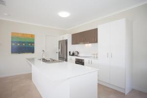 a kitchen with white cabinets and a white counter top at Petrie Beach Holiday Home in Mackay