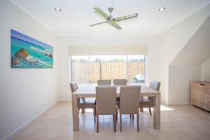 a dining room with a table and chairs and a ceiling fan at Petrie Beach Holiday Home in Mackay