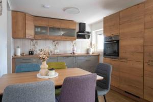 a kitchen with a wooden table and chairs at Vila Jelena - modern spacious apartments near Vintgar Gorge & Bled in Zgornje Gorje +116 photos