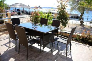 a table and chairs on a patio near the water at Apartments Šuperba in Brodarica