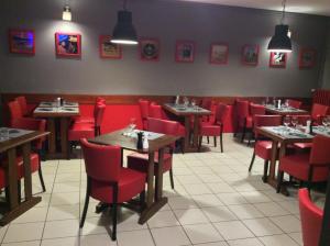 a dining room with red chairs and tables in a restaurant at Logis Hotel Du Champ De Foire in Saint-Aulaye