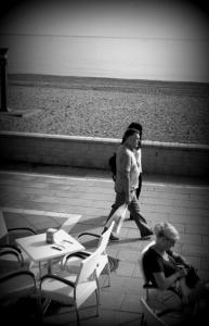a woman walking down a sidewalk next to the beach at Hotel Doña Luisa in San Luis de Sabinillas