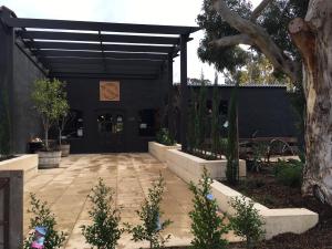 a courtyard with a black building with a tree at One Paddock Currency Creek Winery Villas in Currency Creek