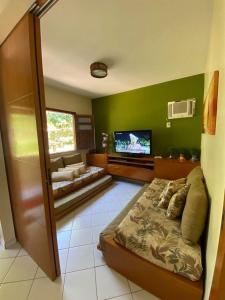 a living room with a bed and a flat screen tv at Village Japara in Ilhéus
