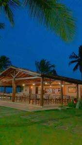 a pavilion with picnic tables and palm trees at night at Village Japara in Ilhéus