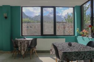 two tables and chairs in a room with windows at Shushabandi Kazbegi in Kazbegi