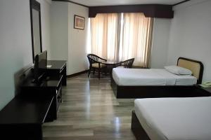 Una habitación de hotel con dos camas, un escritorio y una mesa. en Royal Diamond Hotel, en Phetchaburi 37 fotos más