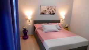 una piccola camera da letto con un letto con lenzuola rosa e bianche di Cairoli Exclusive Rooms & Suite a Brindisi