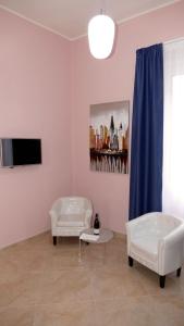 a living room with two white chairs and a tv at Cairoli Exclusive Rooms & Suite in Brindisi