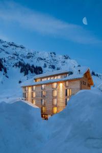 un grand bâtiment dans la neige la nuit dans l'établissement Mondschein Hotel, à Stuben am Arlberg