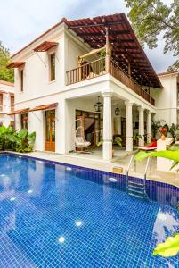 a villa with a swimming pool in front of a house at La Morena, Newly Constructed Luxurious 4 BHK villas in Assagao, Private Pool, Balcony, Kitchen, Patio, Security in Assagao