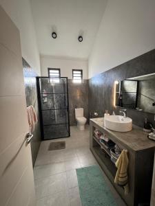 Un baño con lavabo, inodoro y ducha. en Villa TSJ LUXURY, en Tamarin
