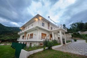 a white house with a porch and a driveway at Hoongla Inn - Homestay in Lumla Tawang in Kāmbāng
