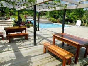 zwei Holzbänke unter einem Pavillon neben einem Pool in der Unterkunft Orator Hotel in Apia