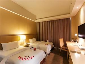 a hotel room with two beds and a television at Jinjiang Metropolo Hotel - Langfang Wanda Plaza in Langfang