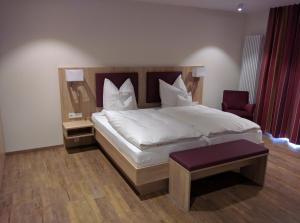 a bedroom with a large white bed and a chair at Hotel Zur-Borke in Neuenrade