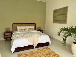 a bedroom with a bed with white sheets and a plant at Villa Kuu - Elegant 2BR Villa with Private Pool in Kerobokan +18 photos