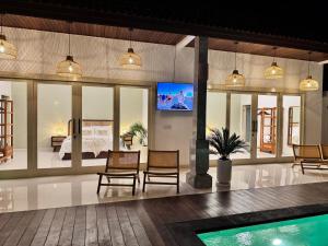 a room with a bed and a tv on a wall at Villa Kuu - Elegant 2BR Villa with Private Pool in Kerobokan