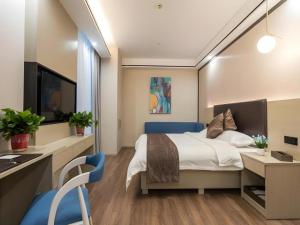 a bedroom with a bed and a desk and a tv at GYA Changzhou Wujin District Hutang New Era Furniture Plaza Hotel in Changzhou