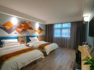 a hotel room with two beds and a painting on the wall at Shell Xinxiang Weibin District Railway Station Department Store Hotel in Xinxiang +215 photos