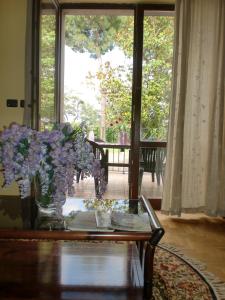 a living room with a glass table with purple flowers at Casina Pian Di Monetto in Montefiascone