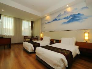 a hotel room with two beds and a painting on the wall at GreenTree Eastern Yantai Development Zone Zhujiang Road Hotel in Yantai