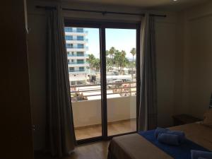 ein Schlafzimmer mit einem Fenster mit Blick auf einen Balkon in der Unterkunft Ithaki Phinikoudes Apartment No. 205 in Larnaka + 55 Fotos