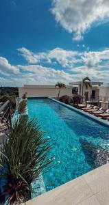图卢姆Experience the charm of Tulum, a unique loft in Aldea Zama的一个带椅子的大型游泳池和一栋建筑